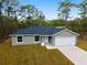 Inviting single-story home showcasing a gray exterior, attached garage, concrete driveway and naturally landscaped front yard at 24354 Nw Water Oak Ave, Dunnellon, FL 34431