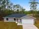 Inviting single-story home showcasing a gray exterior, attached garage, concrete driveway and naturally landscaped front yard at 24354 Nw Water Oak Ave, Dunnellon, FL 34431