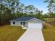Inviting single-story home showcasing a gray exterior, attached garage, concrete driveway and naturally landscaped front yard at 24354 Nw Water Oak Ave, Dunnellon, FL 34431