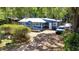Bright blue house with a metal roof, wood porch, and parking for multiple cars on a sunny day at 25292 Ne 132Nd Ln, Fort Mc Coy, FL 32134