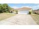 Spacious single-story home with a wide driveway and two-car garage, set against a backdrop of trees at 2730 Sw 162Nd Street Rd, Ocala, FL 34473