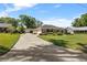 Charming home exterior featuring a long driveway, manicured lawn, and lush landscaping, creating an inviting curb appeal at 4424 Se 14Th St, Ocala, FL 34471