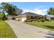 Charming home exterior featuring a long driveway, detached garage, manicured lawn, and lush landscaping at 4424 Se 14Th St, Ocala, FL 34471