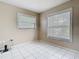 A bright bedroom with neutral walls, tile flooring, and two windows with blinds at 6403 Summit Dr, Orlando, FL 32810