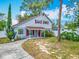 Inviting two-story home featuring a covered front porch, vibrant red shutters, and mature trees at 6403 Summit Dr, Orlando, FL 32810