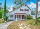 Charming two-story home featuring a covered front porch, vibrant red shutters, and lush landscaping at 6403 Summit Dr, Orlando, FL 32810