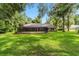 Expansive backyard featuring a screened-in patio area, lush green lawn, and a backdrop of mature trees at 733 Se 67Th Ln, Ocala, FL 34480
