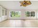 Open living room with tiled floor and backyard views through bright large windows and lush trees at 733 Se 67Th Ln, Ocala, FL 34480