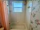 Bathroom showcasing a bathtub with shower, frosted glass window, and floral wallpaper at 7421 Sw 110Th Pl, Ocala, FL 34476