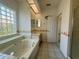 Primary bath with a glass block window above the soaking tub, and marble countertops with and sinks at 7421 Sw 110Th Pl, Ocala, FL 34476