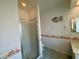Bathroom showcasing an enclosed glass door shower, tile flooring, and decorated wallpaper with vanity and sink at 7421 Sw 110Th Pl, Ocala, FL 34476