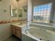 Bright bathroom features a soaking tub with glass block window and a vanity with shell-themed decor at 7421 Sw 110Th Pl, Ocala, FL 34476