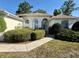 Close-up of the front entrance with arched windows and lush, mature landscaping surrounding the property at 7421 Sw 110Th Pl, Ocala, FL 34476