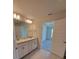 Well-lit bathroom features a double sink vanity with granite counters, cabinets, and an entrance to the bedroom at 8482 Sw 59Th Ter, Ocala, FL 34476