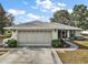 Charming one-story home with a well-manicured lawn, mature shrubbery, and an attached two-car garage at 8990 Se 155Th Pl, Summerfield, FL 34491
