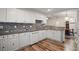 Modern kitchen featuring white cabinets, granite countertops, stainless steel appliances, and wood laminate flooring at 8990 Se 155Th Pl, Summerfield, FL 34491