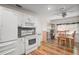 Bright kitchen featuring white appliances and cabinetry, wood floors, a mosaic backsplash, and an adjacent breakfast nook at 8990 Se 155Th Pl, Summerfield, FL 34491