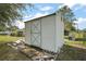 White outdoor shed with X-design door offers additional storage space on the property at 8990 Se 155Th Pl, Summerfield, FL 34491