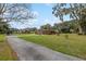 Expansive front yard with a red brick home, carport, gazebo, and a long driveway lined with trees at 9900 Ne 20 Terrace Rd, Anthony, FL 32617