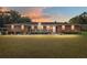 Charming red brick home with inviting front porch, manicured lawn, and lush landscaping at sunset at 9900 Ne 20 Terrace Rd, Anthony, FL 32617