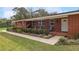 Inviting red brick home featuring a cozy porch with blue Adirondack chairs and well-manicured landscaping at 9900 Ne 20 Terrace Rd, Anthony, FL 32617