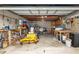 View of the garage interior, showcasing ample storage, exposed rafters and a yellow lawnmower at 9900 Ne 20 Terrace Rd, Anthony, FL 32617