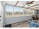A sunroom features a brick wall and wood style floors with bright light from many large windows at 9900 Ne 20 Terrace Rd, Anthony, FL 32617