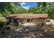 A rear view of home with a cozy sunroom, concrete patio, and a partially fenced yard surrounded by mature trees at 164 Ne 53Rd St, Ocala, FL 34479
