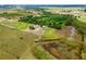 Sprawling land featuring a residence, barn, and green pastures, complemented by a nearby wooded area and distant fields at 22111 Obrien Rd, Howey In The Hills, FL 34737