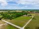 Scenic aerial view showcasing the property's vast green spaces, a long driveway, surrounding woodlands, and a peaceful, rural setting at 22111 Obrien Rd, Howey In The Hills, FL 34737
