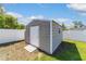 An outdoor storage shed with siding sits on a well-kept lawn, enclosed by a white fence under a partly cloudy sky at 2689 Sw 165Th Street Rd, Ocala, FL 34473