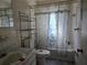 Bathroom with vanity, toilet and tub with decorative curtain and metal storage shelves at 2818 Ne 25Th Ct, Ocala, FL 34470