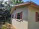 Side view of the house showing a wall with windows and red shutters, near greenery at 2818 Ne 25Th Ct, Ocala, FL 34470