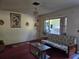 Cozy living room with red carpet, older furniture, and natural light from the window at 2818 Ne 25Th Ct, Ocala, FL 34470