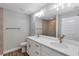 Bright bathroom with double sinks, white cabinets, quartz counters, bronze fixtures, and tile shower at 3 Redwood Track Run, Ocala, FL 34472