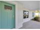 Inviting front door with a teal finish, framed by white trim and a charming porch area at 3 Redwood Track Run, Ocala, FL 34472