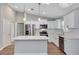 Well-lit kitchen featuring white cabinets, a stainless-steel refrigerator, and an island with pendant lights at 3 Redwood Track Run, Ocala, FL 34472