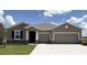 Charming single-story home features a two-car garage, stone accents, and manicured lawn at 3053 Canopy Oak Blvd, Wildwood, FL 34785