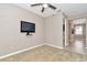 Neutral bedroom with a ceiling fan, mounted TV, and view into hallway's beautiful wood look tile flooring at 3918 Nw 46Th Ter, Ocala, FL 34482