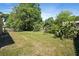 Spacious backyard with lush green grass, mature trees, and partial fence at 5591 Nw 57Th Pl, Ocala, FL 34482
