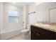 Well-lit bathroom with white tile, granite countertop, and a bathtub with shower at 5591 Nw 57Th Pl, Ocala, FL 34482