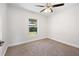 Bright bedroom with plush carpeting, a ceiling fan, and a view of the backyard at 5591 Nw 57Th Pl, Ocala, FL 34482
