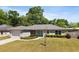 Charming single-story home with a well-manicured lawn, lovely landscaping, and a bright turquoise front door at 5591 Nw 57Th Pl, Ocala, FL 34482