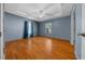 Blue bedroom with wood floors, tray ceiling, ceiling fan, and a window with curtains at 5900 Nw 61St Ct, Ocala, FL 34482