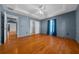 Blue bedroom with wood floors, tray ceiling, ceiling fan, closet, and a window with curtains at 5900 Nw 61St Ct, Ocala, FL 34482