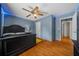 Bedroom with wood floors, blue walls, ceiling fan with lights, and a dark wood bed frame at 5900 Nw 61St Ct, Ocala, FL 34482