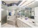 Bathroom with a marble-like tub, white cabinets, and a large mirror reflecting the shower at 6150 Nw 59Th Ave, Ocala, FL 34482