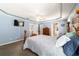 Blue main bedroom featuring a tray ceiling, a wooden bed frame, and an adjacent bathroom at 6150 Nw 59Th Ave, Ocala, FL 34482