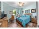Cozy bedroom features warm wood floors, ceiling fan, and natural light from the window at 7167 Sw 99Th Cir, Ocala, FL 34481