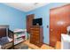 Blue bedroom with wood floors features a crib and a dresser with a TV at 731 Cloverleaf Blvd, Deltona, FL 32725